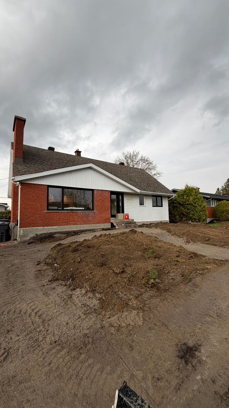 Terrain excavé devant une maison, avant les travaux